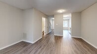 Located at 16 Dansey Cir in Durham, NC, this two-story home offers a well-organized layout across two floors. The main level features durable hardwood-style flooring throughout, a neutral color palette, and a textured ceiling that adds subtle character. The galley-style kitchen is equipped with white cabinetry, light granite-style countertops, a stainless steel refrigerator, and a built-in sink — all opening toward the living area, which is bathed in natural light from a large sliding glass door. A full bathroom with a clean white soaking tub and shower completes the main floor. A carpeted staircase with a warm wood railing leads to the upper level, where both bedrooms are situated. Each bedroom features plush carpet, ceiling fans, and windows that allow natural light to filter in. The primary bedroom stands out with elevated vaulted ceilings, dual closets with built-in shelving, and an adjoining bathroom. The second bedroom also offers dual closets and a ceiling fan. Both bathrooms feature white soaking tub and shower combos. The home's straightforward, functional design and neutral finishes provide a versatile canvas throughout.