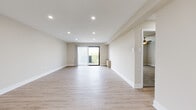 This single-floor residence offers a clean, modern aesthetic throughout its thoughtfully designed layout. The expansive main living area is finished with light-toned wood-style flooring and neutral warm beige walls, creating a bright and welcoming atmosphere. Recessed lighting illuminates the space, while a sliding glass door with vertical blinds opens onto a private balcony, allowing natural light to pour in and providing pleasant outdoor views.

The kitchen features a galley-style layout with a striking contrast of dark lower cabinetry and crisp white upper cabinets, complemented by white quartz countertops and a classic subway tile backsplash. Stainless steel appliances, including a gas range, microwave, and dishwasher, complete this functional and stylish space, all tied together with matching light wood-style flooring.

The bedrooms are carpeted for comfort and each equipped with ceiling fans. Ample closet space is provided with built-in rod systems behind bifold doors. The bathroom showcases large-format neutral tile throughout the walk-in shower enclosure, complete with a glass panel, built-in shelf, and a clean, contemporary finish. The overall design is cohesive, minimal, and move-in ready.