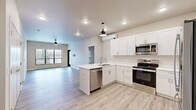 Located at 421 S Green Ave in New Richmond, WI, this well-appointed 2-bedroom, 2-bathroom unit offers a thoughtfully designed single-floor layout with modern finishes throughout. The open-concept kitchen and living area serves as the heart of the home, featuring crisp white shaker cabinetry, white quartz countertops, stainless steel appliances including a range, over-the-range microwave, and dishwasher, along with a peninsula sink and pendant lighting. Light wood-style flooring flows seamlessly through the main living areas, complementing the neutral color palette. The living room is bathed in natural light from large windows and a glass door that opens to a private balcony overlooking the surrounding New Richmond neighborhood. Both bedrooms are generously sized, finished with plush carpet, ceiling fans, and large windows that allow ample natural light. The spacious primary bedroom connects to its own bathroom. Each bathroom is outfitted with white vanity cabinetry, quartz countertops, undermount sinks, and wood-look tile flooring, with stylish matte black hardware and fixtures adding a contemporary accent. Two closets provide practical storage throughout. The unit also features a wall-mounted mini-split system for climate control and recessed lighting throughout the main living areas.