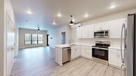 Located at 421 S Green Ave in New Richmond, WI, this well-appointed 2-bedroom, 2-bathroom unit offers a thoughtfully designed single-floor layout with modern finishes throughout. The open-concept kitchen and living area serves as the heart of the home, featuring crisp white shaker cabinetry, white quartz countertops, stainless steel appliances including a range, over-the-range microwave, and dishwasher, along with a peninsula sink and pendant lighting. Light wood-style flooring flows seamlessly through the main living areas, complementing the neutral color palette. The living room is bathed in natural light from large windows and a glass door that opens to a private balcony overlooking the surrounding New Richmond neighborhood. Both bedrooms are generously sized, finished with plush carpet, ceiling fans, and large windows that allow ample natural light. The spacious primary bedroom connects to its own bathroom. Each bathroom is outfitted with white vanity cabinetry, quartz countertops, undermount sinks, and wood-look tile flooring, with stylish matte black hardware and fixtures adding a contemporary accent. Two closets provide practical storage throughout. The unit also features a wall-mounted mini-split system for climate control and recessed lighting throughout the main living areas.
