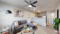 Located on SW Diamond Dr in Bentonville, Arkansas, this single-story unit offers a thoughtfully designed layout with a clean, contemporary aesthetic. Light gray walls, light wood-look flooring, and recessed lighting create a cohesive, modern atmosphere throughout the space.

The living area is open and inviting, anchored by a sectional sofa, glass-top coffee table, and a ceiling fan with integrated lighting. A window allows natural light to fill the room, while a framed art piece adds a decorative touch. The space flows seamlessly into the kitchen, which is separated by a breakfast bar-style counter. The kitchen features gray cabinetry, light quartz-style countertops, a double-basin sink, and stainless steel appliances including a refrigerator, range, and microwave.

The bedroom is comfortably sized with a ceiling fan, a window with exterior views, and direct access to the bathroom. A closet provides built-in storage, and the neutral palette keeps the room feeling calm and airy.

The bathroom features light wood-look flooring consistent with the rest of the unit, a white vanity, a shower/tub combination with a patterned curtain, and framed wall décor that adds a personalized touch. The overall design prioritizes functionality and a clean, modern style.