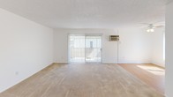 Located at 201 N Wayfield St in Orange, California, this single-floor residence offers a clean, functional layout designed for comfortable everyday living. The open living area is carpeted and filled with natural light streaming through large sliding glass doors fitted with vertical blinds, which lead to an outdoor space. A wall-mounted air conditioning unit keeps the room climate-controlled year-round. The adjacent area transitions to wood-look flooring, connecting seamlessly to the kitchen, which features rich warm-toned cabinetry, granite-style countertops, and a white appliance suite — providing ample storage and prep space. The bedroom is generously proportioned with plush carpet flooring, a ceiling fan with integrated lighting, a large window with vertical blinds allowing natural light, and its own wall-mounted A/C unit. A mirrored sliding closet door adds both storage and visual depth. The bathroom is well-appointed with a wood-tone vanity, granite-style countertop, dual mirrors, and a combined tub and shower enclosed by sliding glass doors with stone-patterned surround walls. Wood-look flooring runs through the bathroom and hallway, tying together the cohesive design of this well-maintained residence.