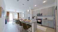 This single-floor, 2-bedroom, 2-bathroom residence delivers a thoughtfully designed open-concept layout with contemporary finishes throughout. The combined kitchen and living area serves as the heart of the home, anchored by a large central island featuring granite countertops, an undermount sink, and pendant lighting overhead. Gray flat-front cabinetry lines the kitchen walls, complemented by stainless steel appliances and light wood-look flooring that extends seamlessly into the living area. Large windows invite generous natural light into the living space, creating a bright and welcoming ambiance.

The primary bedroom is a spacious retreat with room for a king-size bed, ceiling fan, and direct access to a private en-suite bathroom. The primary bath features a dual-sink vanity with granite countertops, gray cabinetry, and a tiled tub-shower combination. A well-sized walk-in closet with full-length hanging rods and upper shelving provides ample storage. The second bedroom is comfortably proportioned, benefiting from natural light and a ceiling fan. The second bathroom mirrors the refined aesthetic of the primary bath, with granite countertops, gray cabinetry, and a tiled tub-shower. Throughout the residence, a neutral color palette and consistent finishes create a cohesive, modern atmosphere.