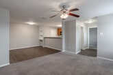 This single-floor residence offers a functional and well-organized layout across two bedrooms and two full bathrooms. The living room serves as the central gathering space, featuring a tile-surround fireplace flanked by multiple windows fitted with horizontal blinds that admit generous natural light. A ceiling fan with an integrated light fixture anchors the room, enhancing comfort and airflow. The neutral carpet and warm beige walls establish a consistent, understated palette throughout.

The galley-style kitchen is equipped with warm wood cabinetry, a double-basin stainless steel sink, light countertops, and black appliances including a refrigerator and range. Wood-look vinyl flooring adds durability and a clean aesthetic to this functional space.

The primary bedroom is a comfortable size, featuring carpet flooring, neutral walls, and a dedicated walk-in closet. The second bedroom similarly offers carpeted flooring and a window with exterior views. Both bedrooms benefit from easy access to their respective full bathrooms, each containing a full tub-shower combination with white tile surround and chrome fixtures. Wood-look flooring in the bathrooms completes the design. A hallway connects all rooms, and each bedroom includes its own closet for practical storage.