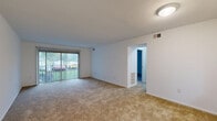 Located at 4002 Sharon Park Lane in Sharonville, Ohio, this 2-bedroom, 1-bathroom residence presents a functional single-floor layout designed for comfortable everyday living. The living room is a welcoming, open space featuring wall-to-wall carpeting and a large sliding glass door fitted with vertical blinds, allowing natural light to flow in while providing a view of the surrounding greenery outside. The layout connects seamlessly to a hallway that leads to the private quarters of the home. Both bedrooms are carpeted and feature clean white walls, creating a bright and neutral atmosphere. The primary bedroom is a well-proportioned room equipped with two sliding closet doors, offering generous storage. The second bedroom also includes a closet and a window that brings in natural daylight. The full bathroom is finished with wood-look vinyl flooring and includes a tiled shower-tub combination with a chrome fixture, a toilet, and a towel bar, maintaining a clean and functional aesthetic. Throughout the home, the consistent use of neutral tones and carpet provides a cohesive, understated look. The unit's compact yet efficient footprint makes it a practical choice for those seeking straightforward, low-maintenance living in Sharonville.