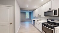 Located at 99 White Horse Pike in Somerdale, NJ, this efficiently designed single-floor unit offers a thoughtfully arranged layout that maximizes every square foot. Light gray walls and light-toned luxury vinyl plank flooring run throughout, creating a clean, cohesive aesthetic.

The kitchen is a standout feature, outfitted with crisp white shaker-style cabinetry with matte black hardware, white quartz countertops, and a full suite of stainless steel appliances including a gas range, over-the-range microwave, dishwasher, and refrigerator. Recessed lighting illuminates the space efficiently. The kitchen flows openly toward the living area, which benefits from multiple windows that invite natural light and offer views of surrounding greenery.

The full bathroom is finished with the same light wood-look flooring and features a white vanity with quartz countertop, a tub-shower combination, and neutral gray walls. Three closets throughout the unit provide generous storage, and a dedicated laundry area adds practical convenience. The unit's entry corridor is wide and welcoming, finished consistently with the rest of the space. Overall, this unit presents a modern, move-in-ready interior with a neutral palette well-suited for a variety of furnishing styles.