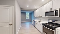 Located at 99 White Horse Pike in Somerdale, NJ, this efficiently designed single-floor unit offers a thoughtfully arranged layout that maximizes every square foot. Light gray walls and light-toned luxury vinyl plank flooring run throughout, creating a clean, cohesive aesthetic.

The kitchen is a standout feature, outfitted with crisp white shaker-style cabinetry with matte black hardware, white quartz countertops, and a full suite of stainless steel appliances including a gas range, over-the-range microwave, dishwasher, and refrigerator. Recessed lighting illuminates the space efficiently. The kitchen flows openly toward the living area, which benefits from multiple windows that invite natural light and offer views of surrounding greenery.

The full bathroom is finished with the same light wood-look flooring and features a white vanity with quartz countertop, a tub-shower combination, and neutral gray walls. Three closets throughout the unit provide generous storage, and a dedicated laundry area adds practical convenience. The unit's entry corridor is wide and welcoming, finished consistently with the rest of the space. Overall, this unit presents a modern, move-in-ready interior with a neutral palette well-suited for a variety of furnishing styles.