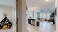 Located at Mystic Pointe in Land O' Lakes, Florida, this single-floor residence offers a well-designed layout with modern finishes and a bright, welcoming ambiance. The open-concept kitchen is outfitted with dark cabinetry, granite countertops, stainless steel appliances including a refrigerator and dishwasher, and pendant lighting over a central island with a sink. Light wood-style flooring flows seamlessly into the adjacent dining area, which features large windows with blinds that flood the space with natural light, and into the spacious living room. The living room is generously proportioned with multiple windows, a ceiling fan, and a warm, comfortable atmosphere. A dedicated dining nook provides an intimate space for meals. The primary bedroom offers vaulted ceilings, plush carpeting, and direct access to a private en-suite bathroom featuring a granite vanity, dark wood cabinetry, tile flooring, and a glass-enclosed walk-in shower. A second bedroom, also carpeted, provides comfortable accommodations and is served by a second full bathroom with a tub-shower combination and a matching granite vanity. Throughout, the residence maintains a cohesive neutral palette, combining modern functionality with a relaxed Florida lifestyle aesthetic.