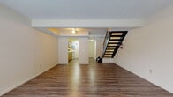 Located at 1997 Mohawk Pl in Kent, Ohio, this two-floor residence offers a practical and well-organized layout across two levels. The main floor features durable hardwood-style flooring throughout the open living area, which is bathed in natural light from a large front-facing window. A ceiling fan with built-in lighting provides comfort and illumination, while a bold black open-tread staircase serves as a functional focal point connecting the two levels. The kitchen is efficiently designed with warm oak cabinetry, white countertops, a double basin sink, and white appliances including a range, microwave, and refrigerator, complemented by hardwood-style flooring that ties into the main living space. A separate entry door provides convenient access directly from the exterior. Upstairs, the carpeted second floor offers multiple generously sized rooms, each with neutral tones and ample natural light through windows with outdoor views. One bedroom features dual reach-in closets with built-in shelving, providing excellent storage capacity. Ceiling fans are present in the upper-level rooms, and a wall-mounted air conditioning unit adds climate control. Throughout both floors, the layout is clean and functional, making this a well-appointed space in a residential Kent neighborhood.