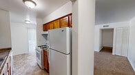 This 2-bedroom, 1-bathroom unit in Indianapolis, IN offers a practical single-floor layout designed for comfortable everyday living. The living room is a notable highlight, featuring warm neutral carpet, bright white walls, and a sliding glass door that fills the space with natural light and provides access to an outdoor area with greenery views. The open sightline from the living room toward the kitchen creates a connected, airy feel throughout the common areas.

The kitchen is equipped with warm oak cabinetry extending to the ceiling for generous storage, dark laminate countertops, a double-basin stainless steel sink, a white gas range, a full-size refrigerator, and a dishwasher. Tile flooring completes the functional cooking space.

Both bedrooms feature neutral carpet and white walls. The primary bedroom includes a closet with bi-fold doors, while the secondary bedroom benefits from a window offering pleasant outdoor views. Hallways connect the rooms efficiently throughout the unit.

The bathroom includes tile flooring, a granite-topped vanity, a full tub-shower combination with chrome fixtures, and clean white walls, providing a straightforward and functional design. Overall, the unit presents a clean, neutral palette throughout.
