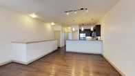 This two-floor residence offers a thoughtfully designed layout that blends modern aesthetics with functional living spaces. The open-concept main living area is anchored by warm hardwood flooring that extends throughout, complemented by track lighting and a ceiling fan that add both style and practicality. A low half-wall elegantly separates the living area from the kitchen, creating a sense of openness while defining each space.

The kitchen is a standout feature, showcasing dark espresso cabinetry, stainless steel appliances including a refrigerator, range, and over-the-range microwave, as well as granite-look countertops and a striking mosaic tile backsplash. Pendant lighting above the peninsula adds a refined touch to the space.

The bedrooms are finished with plush wall-to-wall carpeting and feature windows with blinds that allow natural light to filter in. One bedroom includes a ceiling fan for added comfort. Both bathrooms maintain a cohesive design language, featuring dark cabinetry vanities with granite-look countertops, undermount sinks, and tub-shower combinations with clean white surrounds. Light tile flooring and ample storage cabinetry complete each bathroom. Overall, the residence presents a clean, modern, and move-in-ready environment across both floors.