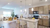 Located at 1000 Oak St. in Reynoldsburg, Ohio, this two-story home offers a thoughtfully designed layout spread across two floors. The main level is anchored by an open-concept kitchen and living room that seamlessly flow together, creating a bright and welcoming communal space. The kitchen is a standout feature, boasting warm-toned cabinetry, stone-look countertops, black appliances, and a large center island with pendant lighting and bar seating — ideal for both cooking and casual dining. Recessed lighting and wood-look flooring carry throughout the main level, adding a clean, contemporary feel. The living area benefits from natural light through well-placed windows and offers generous space for relaxation and entertaining. A staircase connects the main floor to the upper level, where both bedrooms are located, each carpeted and accompanied by closet storage. The primary bedroom features a wide window that fills the room with natural light. Two full bathrooms are finished with stone-look vanity countertops and warm cabinetry. Additional storage is provided by two closets, a utility room, and hallways on both floors. The home also includes an attached garage with a automatic door opener, offering convenient and secure parking.