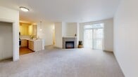 Located at 424 Broadway in downtown Tacoma, WA, this two-bedroom, one-bathroom unit offers a thoughtfully arranged single-floor layout. The open living room is bright and inviting, anchored by a sleek electric fireplace and a large sliding glass door that fills the space with natural light and provides access to an outdoor area. Soft wall-to-wall carpeting runs throughout the living and bedroom areas, contributing to a warm and comfortable atmosphere. The kitchen is well-appointed with light wood cabinetry, stainless steel appliances including a full-size refrigerator, electric range, and built-in microwave, complemented by clean white countertops and wood-look flooring. A peninsula counter connects the kitchen to the living area, enhancing the open flow of the space. Both bedrooms are carpeted and feature crisp white walls; the secondary bedroom includes a sliding closet with built-in racking. The full bathroom is finished with wood-look flooring, a tub-shower combination with tiled surround, a single-sink vanity with light wood cabinetry, and bright overhead lighting. The unit presents a clean, modern aesthetic with a neutral palette throughout, offering a functional and comfortable living environment in the heart of Tacoma.