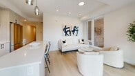 Located at 200 Elgin St in the heart of Ottawa, this well-appointed two-bedroom, two-bathroom residence offers a thoughtfully designed single-level layout with a clean, contemporary aesthetic. Light hardwood flooring flows consistently throughout, anchoring the minimalist design palette of crisp white walls and modern fixtures.

The open-concept living area is bathed in natural light from large floor-to-ceiling windows, creating a bright and airy atmosphere. The space comfortably accommodates a living and dining arrangement, complemented by recessed lighting and stylish pendant fixtures over the kitchen counter.

The primary bedroom features expansive windows that bring in natural light, a sliding closet, and ample space for a full bedroom suite. The second bedroom is equally well-designed, with its own window and light-filled interior. Both rooms showcase the same light hardwood flooring and clean wall finishes seen throughout the residence.

The two bathrooms are finished to a high standard, each featuring large-format tile flooring, sleek vanities with matte black hardware, glass-enclosed showers with elegant black-framed sliding doors, and recessed lighting. A dedicated laundry area and hallway round out the functional layout. This residence offers a refined, modern living experience in a prime Ottawa location.