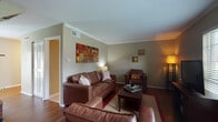 Located in Carbondale, IL, this two-story University Village residence offers a well-designed layout across four bedrooms and two full bathrooms. The main living area features rich hardwood-style flooring, crown molding, and a textured ceiling, creating a warm and inviting atmosphere. Comfortable leather seating surrounds a central coffee table, while a window with blinds allows natural light to filter in alongside the entertainment setup. The kitchen is efficiently arranged with white cabinetry, granite-style countertops, hardwood-style flooring, and a full suite of black appliances including a refrigerator, range, microwave, and dishwasher. Both bathrooms are finished with tile flooring and include a full tub-shower combination. The four bedrooms are carpeted and offer a quiet, comfortable retreat, each with neutral wall tones that provide a versatile backdrop. A staircase connects the two floors, visible in the model overview. The overall ambiance throughout the home is functional and comfortable, making it well-suited for student living or small households seeking ample space in the University Village community.