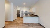 Located at 1810 K St in Lincoln, Nebraska, this well-appointed one-bedroom, one-bathroom unit offers a thoughtfully designed single-floor layout. The open-concept living area seamlessly integrates the kitchen, dining, and living spaces, creating a bright and functional environment. The modern kitchen is a standout feature, equipped with stainless steel appliances including a range, microwave, dishwasher, and refrigerator, complemented by crisp white cabinetry, dark countertops, and a peninsula that provides additional prep and bar seating space. Light-toned luxury vinyl plank flooring runs consistently throughout the unit, adding warmth and cohesion to the clean, neutral palette. The living area benefits from natural light and provides direct access to a private patio through a glass-panel door, offering outdoor space for relaxation. The bedroom is a comfortable, well-sized room with a window and two generously sized closets with double-door paneled entries. Additional conveniences include a dedicated laundry area, a utility room, and hallway storage. The bathroom completes the unit with practical finishes consistent with the modern design throughout. The overall ambiance is clean, contemporary, and move-in ready.