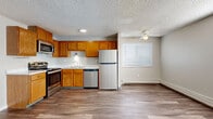 Located at 12661 W Mississippi Ave in Lakewood, Colorado, this single-floor, 2-bedroom, 2-bathroom unit offers a practical and well-organized layout. The open-concept kitchen and living area serves as the heart of the home, featuring warm honey-toned wood cabinetry, stainless steel appliances including a range, microwave, dishwasher, and refrigerator, and a double-basin sink. Wood-style plank flooring runs throughout the main living area, complemented by a ceiling fan and multiple windows fitted with blinds that allow natural light to fill the space. The living room is generously proportioned for the footprint, with a wall-mounted air conditioning unit and baseboard heating providing year-round climate control. A textured ceiling is consistent throughout the unit. Both bedrooms are carpeted and feature neutral gray walls, baseboard heating, and windows with natural light. The primary bedroom connects directly to a closet, and the unit includes a total of five closets, offering notable storage capacity. The bathrooms are clean and functional, with one featuring a full soaking tub surrounded by classic white tile and a privacy window. A connecting hallway ties the rooms together efficiently, creating a cohesive and livable floor plan.