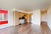 Located at 132 Broadway E in Seattle's vibrant Capitol Hill neighborhood, this two-bedroom, two-bathroom residence offers a thoughtfully designed single-floor layout with modern finishes throughout. The open-concept living, dining, and kitchen area anchors the home, showcasing wide-plank hardwood flooring and a clean, contemporary aesthetic. The kitchen is outfitted with light wood cabinetry, dark countertops, a dark tile backsplash, and a full suite of stainless steel appliances including a French door refrigerator, dishwasher, range, and built-in microwave. A hallway connects the living spaces to the two bedrooms, each featuring hardwood floors, bright white walls, and large windows that bring in natural light and offer views of the surrounding Seattle cityscape. The primary bedroom includes a wall-mounted mini-split HVAC unit for individual climate control. Both bathrooms are finished with white subway tile surrounds, combination tub-shower fixtures with chrome hardware, wood-toned vanity cabinetry, and dark countertops. Three closets provide ample storage throughout. The unit's clean lines, neutral palette, and modern fixtures create a cohesive, move-in-ready living environment.