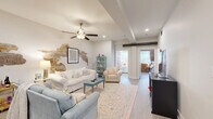 Located on the iconic King Street in Charleston's historic district, this 3-bedroom, 2-bathroom residence masterfully blends historic charm with contemporary finishes across a single, well-organized floor. The living room serves as the heart of the home, featuring an eye-catching exposed brick accent wall that reveals layers of Charleston's storied past alongside crisp white walls, wood-look flooring, recessed lighting, a ceiling fan, and exposed beam details overhead. The kitchen is outfitted with white shaker cabinetry, a subway tile backsplash, stainless steel appliances, and a light quartz peninsula with bar seating — ideal for casual dining. Two hallways guide residents through the layout, connecting the living areas to three comfortable bedrooms, each with ceiling fans and ample closet space. The generously sized primary bedroom offers a tranquil retreat, while the additional bedrooms provide versatility for guests or a home office. Both bathrooms feature white vanities with clean countertops and wood-look tile flooring. Natural light filters throughout the space, enhancing its bright and airy ambiance. This residence offers an authentic Charleston living experience with historic architectural details and modern conveniences in one of the city's most walkable and vibrant neighborhoods.