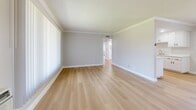Located at 2633 E La Palma Ave in Anaheim, California, this single-story 2-bedroom, 1-bathroom residence offers a thoughtfully designed layout with a clean, modern aesthetic throughout. Light wood laminate flooring flows seamlessly across every room, complemented by crisp white baseboards and crown molding that add a polished, cohesive look.

The open living room is bright and welcoming, featuring large windows with vertical blinds that invite natural light and provide outdoor views. A wall-mounted AC unit ensures year-round comfort. The adjacent kitchen is well-equipped with white shaker-style cabinetry featuring matte black hardware, light stone countertops, a stainless steel gas range with overhead ventilation, and a sink with ample counter space — all finished with recessed lighting overhead.

Both bedrooms are comfortably sized, with the primary bedroom offering generous proportions, a large window, and a closet. The second bedroom is equally bright, with neutral gray walls and a ceiling fan. Crown molding and textured ceilings are consistent throughout the bedrooms, adding architectural character.

The bathroom features a full tub-shower combination with clean white tile surround and chrome fixtures. A connecting hallway ties all rooms together efficiently. This residence offers a bright, move-in-ready feel with consistent, contemporary finishes from end to end.