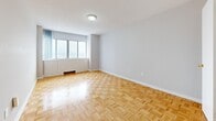 This thoughtfully designed 1-bedroom, 1-bathroom unit offers a comfortable and practical layout across a single floor, with classic parquet wood flooring that flows seamlessly throughout the space, lending warmth and character to every room.

The living room is generously proportioned, bathed in natural light from a wide window that brightens the neutral grey walls and polished parquet floors. A ceiling fan adds a functional touch. The open sightlines from the hallway through to the living area create a sense of depth and continuity.

The kitchen is efficiently laid out with white cabinetry, speckled laminate countertops, tile flooring, and a freestanding electric range — offering ample storage and prep space for everyday cooking.

The spacious primary bedroom comfortably accommodates large furniture and features direct access to a dedicated closet with built-in hanging rails for organized storage. The hallway connects the rooms with ease, and an additional closet provides further storage capacity.

The bathroom is clean and classic, featuring a full-sized soaking tub with white tiled surround. In-unit laundry adds a layer of everyday convenience. Overall, the unit presents a bright, neutral palette and a practical, well-connected floor plan suited to a variety of lifestyles.