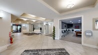 Located at 5 Promenade Blvd in Fair Lawn, NJ, this well-appointed amenity floor offers residents a refined and welcoming communal environment. The main lobby greets visitors with large-format porcelain tile flooring, recessed tray ceilings with flush-mount lighting, and a striking mosaic tile accent wall that adds texture and visual depth to the space. Comfortable seating areas furnished with contemporary white tufted lounge chairs and a sofa provide residents with inviting spaces to gather or relax.

Adjacent to the lobby, a dedicated seating nook features tufted white accent chairs, a chrome-and-glass side table, and curated wall art, creating a quiet, boutique-style retreat. Glass-paneled French doors lead to a fitness center equipped with cardio and exercise machines, visible through the paned windows and flooded with interior light.

A separate game room, finished with textured wave-pattern wallcovering and wainscoting, offers recreational amenities including a full-size billiards table, foosball table, bar-height seating, and wall-mounted televisions — ideal for social gatherings. The building entry vestibule features glass double doors and clean, neutral finishes that set a polished tone throughout. Every area reflects a cohesive modern aesthetic with thoughtful design details.