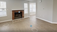 This single-story residence offers 760 square feet of thoughtfully designed living space. The home features three bedrooms, including a primary bedroom of 140 square feet, and one full bathroom. The heart of the home is a combined kitchen and living area, showcasing a brick fireplace as a focal point. The kitchen boasts white cabinetry, black appliances, and a practical L-shaped layout with a breakfast bar.

Throughout the home, wood-look flooring and light gray walls create a cohesive, contemporary aesthetic. Large windows with white plantation shutters allow ample natural light to flood the space. The bathroom is outfitted with a white vanity, tub-shower combination, and modern fixtures. A dedicated laundry room adds convenience to daily life.

Additional features include recessed lighting, ceiling fans, and ample closet space. The neutral color palette and updated finishes provide a move-in ready home with a fresh, modern feel. Despite its compact size, the efficient floor plan maximizes usable space, making this an ideal option for those seeking a low-maintenance yet comfortable living environment.