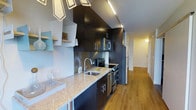 Located at 3737 Chestnut St in Philadelphia, PA, this single-floor space offers a thoughtfully designed interior with a contemporary aesthetic. The kitchen is a standout feature, showcasing floor-to-ceiling dark espresso cabinetry that creates a bold, modern contrast against the light granite countertops. Stainless steel appliances, including a range, microwave, and refrigerator, are seamlessly integrated into the layout, complemented by a sleek undermount sink with a modern arc faucet. Track lighting runs along the ceiling, providing focused illumination throughout the kitchen. The warm hardwood flooring extends from the kitchen down the hallway, creating a cohesive flow throughout the space. A decorative wall mural adds a unique artistic touch, reflecting a creative and urban character. The hallway leads to additional rooms, suggesting a well-organized and functional floor plan. Overall, the space combines high-end finishes with practical design, making it well-suited for those who appreciate modern urban living in the heart of Philadelphia.