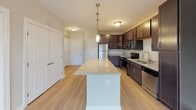 Located at 5724 Dixie River Rd in Charlotte, NC, this single-floor residence offers a well-designed layout with thoughtful finishes throughout. The kitchen serves as a central highlight, showcasing rich dark cabinetry, granite countertops, and a full suite of stainless steel appliances including a refrigerator, range, microwave, and dishwasher. A large kitchen island with matching granite provides additional prep and dining space, while pendant lighting adds a polished touch. Light hardwood-style flooring flows seamlessly through the open-concept living and kitchen areas, creating a bright and cohesive aesthetic. The bedroom features plush carpet and a ceiling fan, with a window fitted with blinds that allows natural light to filter in comfortably. An additional room with hardwood-style flooring and window treatments offers flexible use as a bedroom or office. The bathroom is finished with a dark vanity, granite countertop, a framed mirror, and a walk-in shower with tiled surround. Neutral wall tones, white trim, and consistent hardware finishes throughout the home contribute to a clean, modern ambiance well-suited for comfortable everyday living in the Charlotte area.