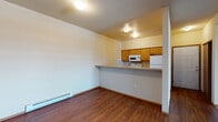 Located at 5015 South Regal Street in Spokane, Washington, this single-floor residence offers a well-organized layout designed for comfortable everyday living. The entryway opens into a combined living and dining area, where warm hardwood-style flooring transitions seamlessly to plush carpet in the living space. A sliding glass door floods the room with natural light and provides outdoor access. The kitchen features a peninsula counter that opens to the dining area, warm wood cabinetry, light countertops with a tile backsplash, and white appliances including a refrigerator, range, microwave, and dishwasher. A hallway connects the main living areas to the private quarters. The carpeted bedrooms are generously sized, with one offering an ensuite bathroom and views of the surrounding greenery through a large window. Two full bathrooms are present in the unit — one with a single-sink vanity with wood cabinetry and a shower/tub combo, and a second with a well-lit vanity and mirror. Additional utility space is accessible within the unit, housing a water heater. Baseboard heating is present throughout the home. The clean, neutral palette and functional design make this a practical and comfortable Spokane residence.