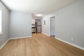 Located at 110 Garrett Dr in Athens, Alabama, this single-story unit offers a straightforward, functional layout finished with consistent light wood flooring that runs throughout the entire space, lending warmth and visual continuity from room to room. The walls are painted in a soft, cool gray tone, creating a clean and understated atmosphere that complements the bright white baseboards and trim.

The open living area is spacious enough to accommodate comfortable furnishings and flows naturally toward the kitchen. The kitchen is efficiently designed, featuring white cabinetry, a stainless steel refrigerator, a stainless steel dishwasher, a double-basin sink, and light countertops — providing all essential appliances in a compact, well-organized space. A utility panel is conveniently accessible just off the kitchen area.

The bedrooms are well-proportioned, each featuring windows fitted with horizontal blinds that allow natural light to filter in. One bedroom includes a closet with built-in shelving. The bathroom is clean and functional, equipped with a full tub-shower combination and standard fixtures in a neutral palette. Textured ceilings are present throughout, and HVAC vents are integrated into the flooring for efficient climate control across the unit.