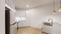 Located at 1105 Sunset Crest Lane in Summerville, SC, this one-bedroom, one-bathroom residence offers a thoughtfully designed single-floor layout with a clean, modern aesthetic throughout. Light wood-look flooring and crisp white walls create a bright, cohesive feel from room to room.

The open-concept kitchen and living area serves as the heart of the home. The kitchen is outfitted with white cabinetry featuring gold-toned hardware, a subway tile backsplash, stainless steel appliances, and a peninsula with a double-basin sink and grey quartz-style countertops. Elegant gold pendant lights hang above the peninsula, complementing the recessed lighting overhead. A built-in upper wine rack adds a distinctive touch near the entryway.

The living area flows naturally from the kitchen, featuring a ceiling fan with a gold-accented fixture and French doors that invite natural light and outdoor access. The spacious bedroom continues the consistent design language with matching flooring, a ceiling fan, and a window with blinds. It is complemented by a dedicated walk-in closet with wire shelving for ample storage.

The bathroom is well-appointed with a grey-toned vanity, gold hardware accents, a framed mirror with lighted fixture, and a combined tub and shower. A hallway connects all rooms efficiently, completing this well-organized and stylish residence.