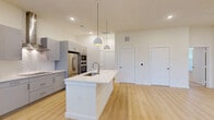 Located at 33200 Forest West St in Magnolia, TX, this modern single-story home offers a thoughtfully designed open-concept layout that seamlessly connects the living, dining, and kitchen areas. The kitchen is a standout feature, showcasing grey flat-front cabinetry, white quartz countertops, a large center island with an undermount sink, pendant lighting, a subway tile backsplash, a stainless steel appliance suite including a double wall oven and French door refrigerator, a sleek range hood, and a built-in wine refrigerator. Light wood-look flooring runs throughout the main living areas, enhancing the bright, airy ambiance. A dedicated pantry provides additional storage. The spacious bedroom features plush carpeting, a ceiling fan, and natural light from large windows. Two well-appointed bathrooms include white quartz vanities, grey cabinetry with brushed nickel hardware, large-format tile flooring, and a glass-enclosed shower with decorative tile accents. Two closets, including a walk-in with built-in shelving and hanging rods, offer ample storage. A garage completes this well-equipped home.