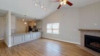 Located at 5349 Niblick Ct in High Point, NC, this two-story home is designed with a practical and modern layout that maximizes both comfort and functionality. The main level centers around an open-concept living and kitchen area distinguished by soaring vaulted ceilings and a ceiling fan overhead. Light-toned hardwood-style flooring flows throughout the main level, contributing to a bright and cohesive aesthetic. The kitchen is well-appointed with gray shaker-style cabinetry, granite countertops, a tile backsplash, and stainless steel appliances including a range, over-the-range microwave, and refrigerator. A peninsula with an integrated sink provides additional prep space and casual seating. Track lighting and pendant fixtures illuminate the kitchen, while a window admits natural light into the dining area. A powder room on the main level features a pedestal sink, oval mirror, and hardwood-style flooring. Upstairs, carpeted bedrooms offer a quiet retreat, with one featuring dual windows and a ceiling fan. A full bathroom on the upper level is finished with marble-style tile flooring, a granite vanity, and dark cabinetry. A spacious walk-in closet with wire shelving provides generous storage. A dedicated laundry room with a window and washer/dryer connections completes the upper floor.