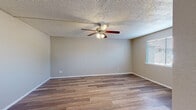 This single-floor unit offers a cohesive and functional layout, finished with wood-look flooring that flows consistently throughout each room, lending a warm and unified aesthetic to the entire space.

The living area is generously sized, featuring neutral-toned walls, clean white baseboards, and a textured ceiling with a ceiling fan and integrated light fixture. Multiple windows fitted with horizontal blinds allow ample natural light to fill the room, creating a bright and airy atmosphere.

Adjacent to the living space is a well-lit dining area, also benefiting from large windows that overlook greenery outside. The open sightline between the dining and kitchen areas promotes a connected, practical flow.

The kitchen is thoughtfully designed with gray cabinetry, stone-look countertops, and a subway-tile backsplash in neutral tones. It includes a full suite of white appliances — refrigerator, range, dishwasher — along with a stainless steel sink and ample upper and lower cabinet storage. A built-in range hood and overhead lighting complete the functional cooking space.

The bathroom includes wood-look flooring, a vanity with gray cabinetry and stone-look countertop, a built-in linen tower for additional storage, and a tub-shower combination with tile surround. A window provides natural ventilation and light to the space.