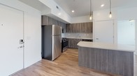 This well-appointed single-floor unit showcases a thoughtfully designed layout that balances functionality and modern style throughout. The open-concept kitchen is a standout feature, outfitted with full stainless steel appliances including a gas range, built-in microwave, refrigerator, and dishwasher. Rich wood-tone cabinetry extends floor to ceiling, complemented by light quartz countertops, a tile backsplash, and a peninsula that provides additional prep and dining space. Warm wood-look luxury flooring runs throughout the kitchen and main living areas, while recessed and pendant lighting adds a contemporary touch.

The bedrooms offer a comfortable retreat, each carpeted in neutral tones and filled with natural light through horizontal-blind-fitted windows that offer outdoor views. Ceiling fans provide additional comfort and airflow.

The bathrooms are finished with consistent, modern detailing. The full bath features a tub-shower combination with built-in shelving and wood-look flooring, while a separate vanity area includes a wood-tone cabinet, white countertop, large mirror, and bright vanity lighting. Clean white walls and crisp trim work carry throughout the unit, creating a cohesive, bright, and welcoming atmosphere from room to room.
