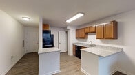 This single-floor residence at 2501 S 4th St in Louisville, Kentucky offers a practical and comfortable layout with clean, modern finishes throughout. The kitchen serves as a central feature of the home, showcasing warm honey-toned wood cabinetry, speckled granite countertops, and black appliances including a refrigerator, range, and dishwasher. A peninsula with a matching granite surface provides additional prep space and a casual dining option, while durable wood-look flooring ties the area together seamlessly. The layout connects the kitchen to the living area, offering an open and functional flow throughout the main living space. The bedroom is a well-proportioned room with wood-look flooring, neutral walls, and a large window fitted with blinds that allows natural light to fill the space. The bathroom features a tub-shower combination with a curtain, a vanity with dark wood cabinetry, and matching wood-look flooring that continues the cohesive aesthetic found throughout the home. White walls and clean finishes give the entire residence a bright and move-in-ready feel. The overall design emphasizes practicality and comfort, making it a functional living space in the heart of Louisville.