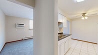 Located at 321 Larpenteur Ave E in Maplewood, Minnesota, this single-floor unit offers a practical and well-organized layout across three bedrooms, a living room, kitchen, and hallway. The galley-style kitchen is outfitted with white cabinetry, dark countertops, a stainless steel double sink, white tile flooring, and white appliances including a refrigerator and range. It opens conveniently to the hallway, connecting the main living areas. The living room is generously proportioned, featuring soft carpet, a large sliding window that floods the room with natural light and offers wooded outdoor views, and a wall-mounted air conditioning unit alongside baseboard heating. Each of the three bedrooms is carpeted and finished with neutral tones and warm wood-toned baseboards. The primary bedroom includes a walk-in closet, while additional bedrooms feature either mirrored sliding-door closets or standard reach-in closets. Several bedrooms benefit from windows with natural wooded views and baseboard heating. Throughout the unit, the design is clean and understated, emphasizing functionality. The consistent use of light neutral walls, soft carpet, and white trim creates a cohesive and comfortable atmosphere throughout.