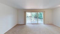 This single-floor, one-bedroom, one-bathroom residence is thoughtfully laid out to maximize comfort and functionality. The living area features soft wall-to-wall carpeting, clean white walls, and a standout sliding glass door that opens to a private balcony with wrought-iron railings and lush greenery views, filling the room with natural light. The kitchen is efficiently designed with warm wood cabinetry, white countertops, hardwood-style flooring, and white appliances including a gas range and full-size refrigerator, offering everything needed for everyday cooking. A carpeted hallway connects the main living spaces and includes a double-door closet, providing ample additional storage. The bedroom is a comfortable, light-filled retreat with a window overlooking the outdoors, plush carpet, and an expansive closet system with bifold doors and built-in shelving and hanging rods. The full bathroom is clean and straightforward, featuring a vanity with warm wood cabinetry, a tiled tub-shower combination, and tile flooring. Throughout, the space maintains a neutral, move-in-ready aesthetic with consistent finishes that offer a calm and practical living environment.