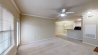Located in Lafayette, Louisiana, this single-story 2-bedroom, 2-bathroom unit offers a practical and comfortable layout across a generously sized floor plan. The open living area features neutral-toned carpet, crown molding, and a ceiling fan, creating a bright and airy atmosphere. Large windows allow natural light to fill the room, with access to an exterior door for added convenience. The living space flows seamlessly into the dining area and kitchen, which is defined by a peninsula-style breakfast bar with dark granite-style countertops. The kitchen is well-equipped with warm wood cabinetry, a black refrigerator, electric range, and built-in microwave, complemented by wood-look flooring. Both bedrooms are carpeted and generously proportioned, each featuring ceiling fans and ample wall space. Natural light enters through sizable windows fitted with blinds. The two bathrooms are functional and clean, with one featuring a tub/shower combo, wood-look flooring, and wood-toned vanity cabinetry with dark countertops. Crown molding and consistent neutral wall tones throughout lend the unit a cohesive, polished look. The overall ambiance is calm, practical, and move-in ready.
