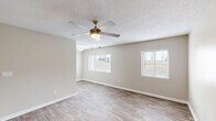 This 1-bedroom, 1-bathroom unit in Augusta, Georgia offers a clean, modern aesthetic with consistent wood-look flooring and neutral warm-beige walls throughout. The combined kitchen and living area forms the heart of the unit, with the living room featuring two windows fitted with white horizontal blinds that invite natural light, complemented by a ceiling fan with integrated lighting and a textured ceiling. The kitchen is thoughtfully appointed with white shaker-style cabinetry, granite-look countertops, a classic white subway tile backsplash, a double-basin stainless steel sink, and stainless steel appliances including a refrigerator and electric range. The spacious bedroom provides a comfortable retreat, featuring a ceiling fan, a natural-light window, and two closets with bifold doors for generous storage. The bathroom continues the clean, classic aesthetic with a full tub-and-shower combination surrounded by crisp white subway tile and chrome fixtures. A dedicated closet completes the layout, adding practical storage options. Throughout the unit, white baseboards and trim provide a polished finish, tying together the cohesive, move-in-ready design of this Augusta residence.