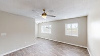 This 1-bedroom, 1-bathroom unit in Augusta, Georgia offers a clean, modern aesthetic with consistent wood-look flooring and neutral warm-beige walls throughout. The combined kitchen and living area forms the heart of the unit, with the living room featuring two windows fitted with white horizontal blinds that invite natural light, complemented by a ceiling fan with integrated lighting and a textured ceiling. The kitchen is thoughtfully appointed with white shaker-style cabinetry, granite-look countertops, a classic white subway tile backsplash, a double-basin stainless steel sink, and stainless steel appliances including a refrigerator and electric range. The spacious bedroom provides a comfortable retreat, featuring a ceiling fan, a natural-light window, and two closets with bifold doors for generous storage. The bathroom continues the clean, classic aesthetic with a full tub-and-shower combination surrounded by crisp white subway tile and chrome fixtures. A dedicated closet completes the layout, adding practical storage options. Throughout the unit, white baseboards and trim provide a polished finish, tying together the cohesive, move-in-ready design of this Augusta residence.