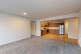 Located at 16003 Admiralty Way in Lynnwood, Washington, this two-bedroom, two-bathroom apartment offers a well-designed, single-floor layout with a thoughtful blend of comfort and functionality. The open-concept living, dining, and kitchen area serves as the heart of the home, where light-toned luxury vinyl plank flooring transitions seamlessly into plush carpeting in the living space. The kitchen is outfitted with contemporary flat-front cabinetry in a warm wood finish, light countertops, and a full suite of stainless steel appliances including a refrigerator, range, microwave, and dishwasher. Recessed lighting adds a clean, modern touch overhead. The living area is generously sized and benefits from natural light through large windows, with access to a private balcony. Both bedrooms are carpeted and feature windows that bring in natural light, with the spacious primary bedroom offering a comfortable retreat. Five closets throughout the unit provide exceptional storage capacity. A central hallway connects the bedrooms and two full bathrooms, which feature wood-toned cabinetry and light stone-finish countertops. The overall aesthetic is clean, neutral, and move-in ready.