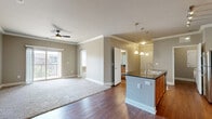 Located at 8515 Clearwater Ln in Indianapolis, Indiana, this well-appointed 2-bedroom, 2-bathroom residence offers a thoughtfully designed single-level layout. The open-concept kitchen and living area serves as the heart of the home, where rich hardwood flooring, crown molding, and arched doorways lend a refined architectural character throughout. The kitchen is equipped with warm wood cabinetry, dark granite countertops, stainless steel appliances including a refrigerator, gas range, and microwave, plus a built-in wine cooler and a central island with a sink — ideal for both cooking and entertaining. Pendant lighting over the island and track lighting above the counters provide functional, layered illumination. The adjacent living room features a ceiling fan, neutral carpet, and a sliding glass door that invites natural light and outdoor access. The spacious primary bedroom includes plush carpet, crown molding, a ceiling fan, and a generous walk-in closet with wire shelving. The second bedroom also offers carpet, a ceiling fan, and a bright window. Both bathrooms are appointed with granite vanities, wood cabinetry, and hardwood floors, with one featuring a glass-enclosed shower. A dedicated laundry room with side-by-side washer and dryer completes this functional and well-finished home.