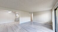 Located at 150 S Wood Ave in Oakdale, California, this single-floor unit offers a clean, neutral aesthetic throughout. Light-toned luxury vinyl plank flooring runs continuously across all living spaces, providing a cohesive and easy-to-maintain foundation. Textured popcorn ceilings and warm beige walls create a consistent backdrop in every room.

The open living area is generously proportioned, featuring multiple wall vents for climate control and a sliding glass door that opens to a private patio, allowing natural light to fill the space. An adjacent area offers additional flexibility for dining or secondary living use.

The galley-style kitchen is well-equipped with gray shaker cabinets lining both walls, light stone-pattern countertops, a stainless steel refrigerator, an electric range, a dishwasher, and recessed lighting overhead. A pass-through opening connects the kitchen visually to the main living area.

The bedroom areas include rooms with windows fitted with horizontal blinds, as well as spaces featuring dual six-panel doors leading to closets. Additional rooms provide versatile configurations suitable for sleeping or office use.

The unit's layout, as reflected in the dollhouse view, is compact yet functional, with well-defined zones for living, cooking, and sleeping — making it a practical and move-in ready space in a residential Oakdale neighborhood.