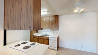Located at 633 Ascot #88 in Vista, this single-floor unit offers a straightforward and functional layout across well-defined living spaces. The kitchen is equipped with warm wood-toned cabinetry extending from floor to ceiling, providing generous storage throughout. White appliances include a coil-burner range, refrigerator, and dishwasher, complemented by light countertops and a double-basin sink. Tile-style flooring runs through the kitchen, while the remainder of the unit features neutral wall-to-wall carpeting that adds a sense of warmth. The living area is open and bright, with a textured ceiling and a sliding glass door that allows natural light to fill the space and offers a view to the outdoors. A wall-mounted A/C unit provides climate control. The bedroom is a well-proportioned, carpeted room with a window dressed in vertical blinds, admitting natural light and exterior views. A hallway connects the bedroom to the full bathroom, which includes a tub-shower combination, a toilet, a single-sink vanity with wood-accented cabinetry, and a mirrored medicine cabinet. The textured ceilings are consistent throughout, giving the unit a cohesive character. Overall, the space delivers a clean, functional environment suited for comfortable everyday living.