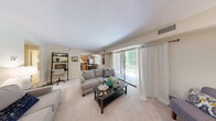This thoughtfully designed 2-bedroom, 1-bathroom residence offers a comfortable and functional single-floor layout. The living room serves as the heart of the home, featuring plush carpeting, neutral tones, and a large sliding glass door that floods the space with natural light and provides views of lush greenery outdoors. The room offers flexible space for both lounging and a dedicated work area.

The kitchen is well-equipped with warm honey-toned wood cabinetry, dark countertops, stainless steel appliances including a gas range, refrigerator, and dishwasher, and light tile flooring. A dining area adjacent to the kitchen comfortably accommodates a small table, making it ideal for everyday meals.

The primary bedroom is a generously sized retreat with soft carpeting, large windows with outdoor views, and ample room for full bedroom furnishings. The second bedroom offers similar comfort and natural light. Both bedrooms benefit from the residence's four closets, providing exceptional storage throughout.

The bathroom features a full soaking tub and shower combination in a clean, neutral finish. A connecting hallway ties all rooms together efficiently, creating a smooth and cohesive flow throughout the home. Overall, the space presents a warm, inviting ambiance with practical amenities suited for comfortable everyday living.