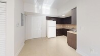 Located at 642 SW 1st St in Miami's vibrant Brickell neighborhood, this one-bedroom, one-bathroom unit offers a well-organized layout across a single floor. The living room is bright and airy, featuring large sliding glass doors that open onto a private balcony, flooding the space with natural light and polished tile floors that reflect the Miami sunshine. The kitchen is thoughtfully designed with dark espresso cabinetry extending to the ceiling for ample storage, a neutral tile backsplash, light stone countertops, and a full suite of appliances including a refrigerator, electric range, and built-in microwave. The bedroom is a comfortable, sunlit retreat with a window fitted with blinds for privacy and light control, and direct access to a spacious walk-in closet equipped with wire shelving and dual hanging rods. The full bathroom features a clean, white finish with a tub-shower combination, a dark-cabineted vanity with a stone countertop, and tile flooring. Additional highlights include a dedicated laundry area and a utility room, offering practical convenience. Throughout the unit, light-toned large-format tile flooring and crisp white walls create a clean, modern aesthetic consistent with Miami's contemporary residential style.
