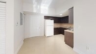 Located at 642 SW 1st St in Miami's vibrant Brickell neighborhood, this one-bedroom, one-bathroom unit offers a well-organized layout across a single floor. The living room is bright and airy, featuring large sliding glass doors that open onto a private balcony, flooding the space with natural light and polished tile floors that reflect the Miami sunshine. The kitchen is thoughtfully designed with dark espresso cabinetry extending to the ceiling for ample storage, a neutral tile backsplash, light stone countertops, and a full suite of appliances including a refrigerator, electric range, and built-in microwave. The bedroom is a comfortable, sunlit retreat with a window fitted with blinds for privacy and light control, and direct access to a spacious walk-in closet equipped with wire shelving and dual hanging rods. The full bathroom features a clean, white finish with a tub-shower combination, a dark-cabineted vanity with a stone countertop, and tile flooring. Additional highlights include a dedicated laundry area and a utility room, offering practical convenience. Throughout the unit, light-toned large-format tile flooring and crisp white walls create a clean, modern aesthetic consistent with Miami's contemporary residential style.