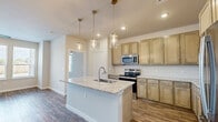 Located at 8740 Youree Dr in Shreveport, Louisiana, this single-story, 3-bedroom, 2-bathroom home offers a thoughtfully designed open-concept floor plan. The kitchen serves as the heart of the home, showcasing granite countertops, a central island with a sink, warm-toned cabinetry, a white subway tile backsplash, and stainless steel appliances including a range, microwave, and refrigerator. Stylish pendant lighting illuminates the island, complementing recessed ceiling lights throughout. Wood-look flooring extends through the main living areas, while the spacious living room features a ceiling fan and a trio of windows that invite ample natural light. The three bedrooms are carpeted and each include ceiling fans and windows overlooking the outdoors. The primary bedroom includes access to a generously sized walk-in closet with built-in shelving and a private en-suite bathroom featuring a double vanity with granite countertops, wood-look flooring, and a glass-enclosed walk-in shower with subway tile. The second bathroom mirrors the same quality finishes with a tub-shower combination. A dedicated laundry area with in-unit washer and dryer hookups adds everyday convenience. Six closets throughout the home provide abundant storage.